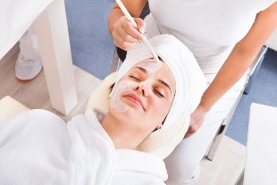 The beautician applies a mask to the face